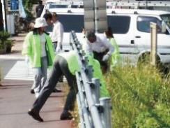 複数人で歩道横の草むらに落ちているゴミ拾いをしている写真